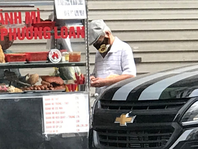 4 Hình chụp từ xa anh Lan đang mua bánh mỳ